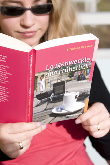 Foto: junge Frau liest  Taschenbuch Laugenweckle zum Frühstück